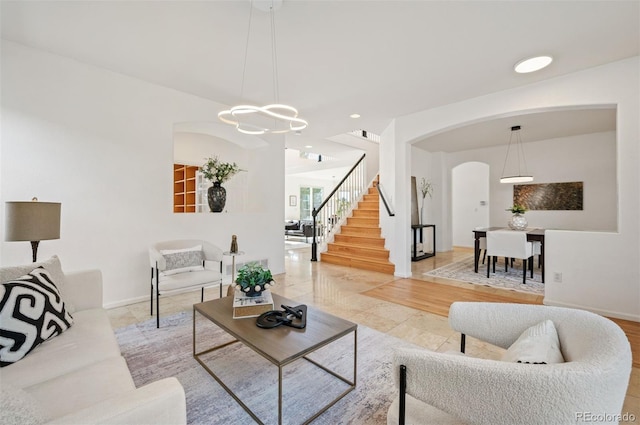 living room with baseboards, light tile patterned floors, an inviting chandelier, stairs, and arched walkways