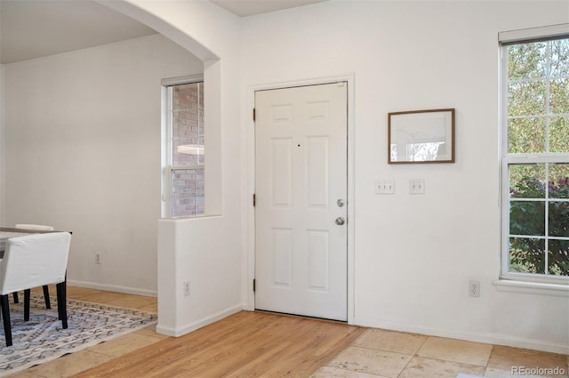entrance foyer with arched walkways, a wealth of natural light, and baseboards