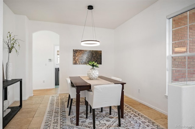 dining space with light tile patterned floors, baseboards, and arched walkways