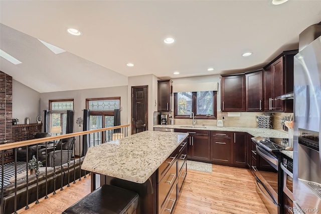 kitchen featuring vaulted ceiling, a center island, stainless steel appliances, sink, and light wood-type flooring