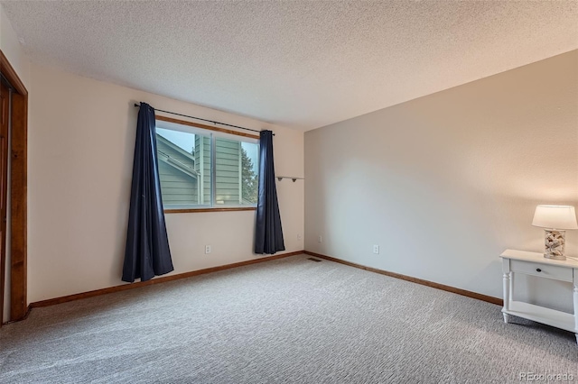 spare room featuring a textured ceiling and carpet