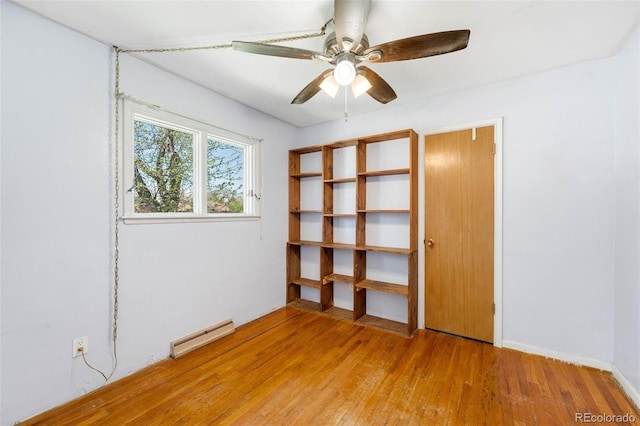 empty room with a baseboard heating unit, wood finished floors, and ceiling fan