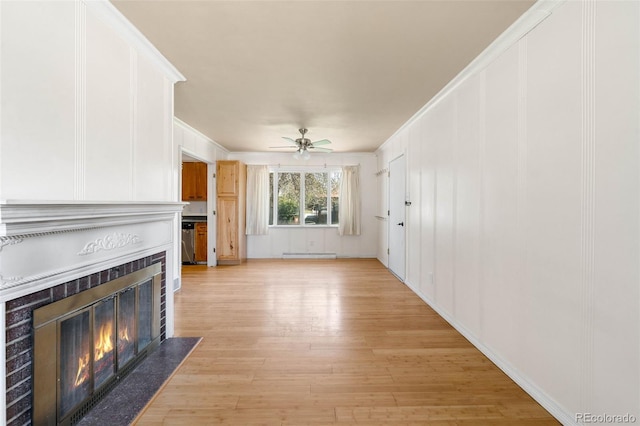 unfurnished living room with a tile fireplace, light wood-style flooring, a ceiling fan, and crown molding