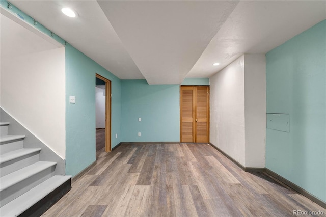 empty room featuring wood finished floors, recessed lighting, baseboards, and stairs