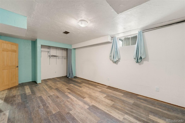 unfurnished bedroom with wood finished floors, a textured ceiling, and a closet