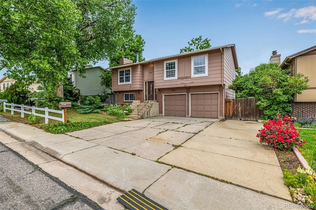 9832 High St, Thornton, CO 80229 - bi-level home featuring brick siding, a chimney, an attached garage, and driveway