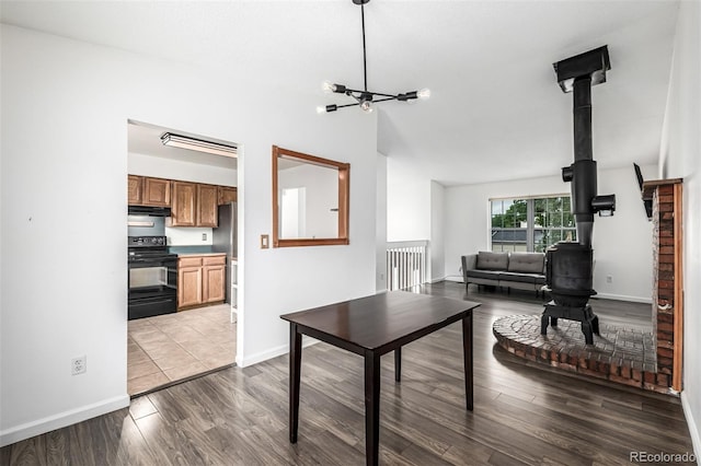 9832 High St, Thornton, CO 80229 - living area with a wood stove, wood finished floors, baseboards, a chandelier, and vaulted ceiling