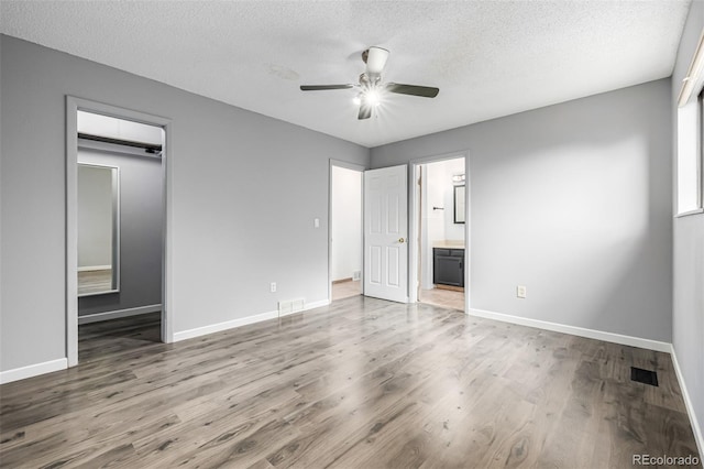 9832 High St, Thornton, CO 80229 - unfurnished bedroom featuring wood finished floors, a textured ceiling, baseboards, and a walk in closet