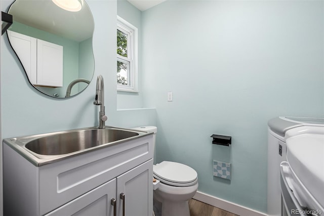 9832 High St, Thornton, CO 80229 - bathroom with washing machine and clothes dryer, wood finished floors, vanity, toilet, and baseboards
