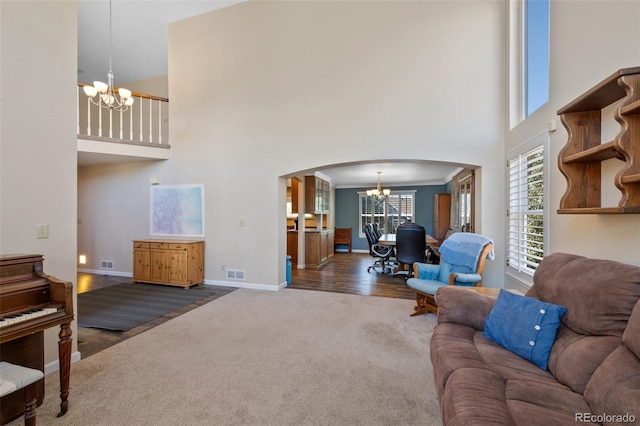 living room with a high ceiling, ornamental molding, dark wood-type flooring, and a notable chandelier