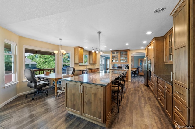 kitchen featuring hanging light fixtures, dark stone countertops, dark hardwood / wood-style flooring, a textured ceiling, and a notable chandelier