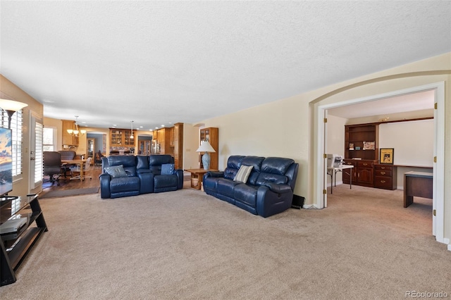 living room featuring a notable chandelier, a textured ceiling, and carpet floors