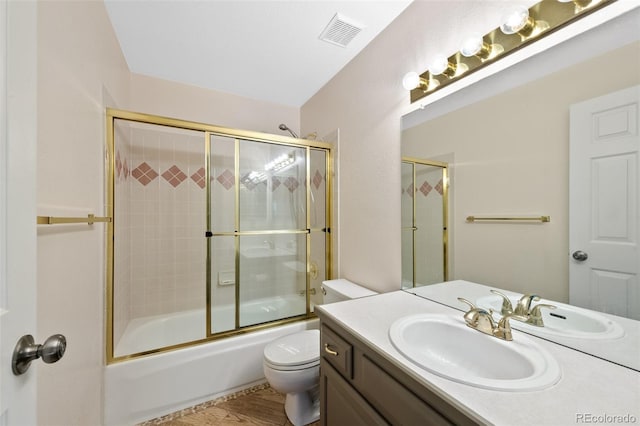 full bathroom featuring hardwood / wood-style floors, vanity, toilet, and bath / shower combo with glass door