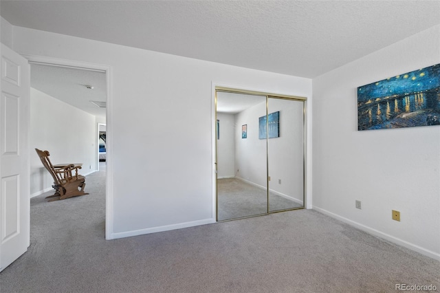 unfurnished bedroom featuring a textured ceiling, carpet, and a closet