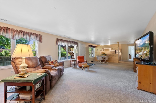 living room featuring wooden walls and light colored carpet