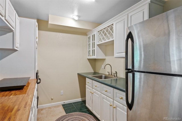 kitchen with white cabinets, stainless steel fridge, sink, and butcher block countertops