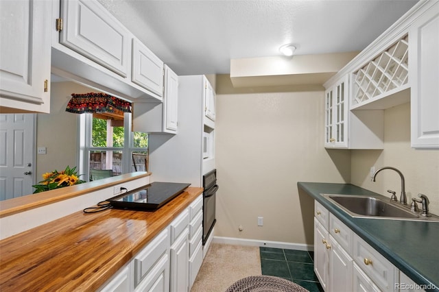 kitchen featuring white cabinets, dark tile patterned flooring, sink, oven, and butcher block counters