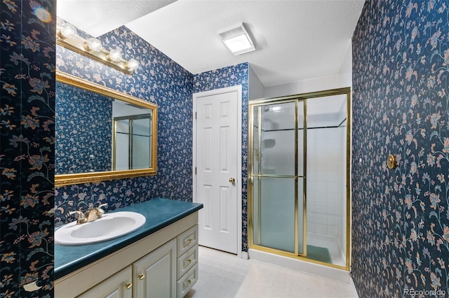 bathroom featuring a textured ceiling, vanity, and a shower with door