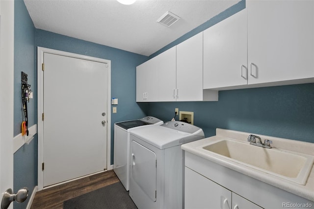 laundry area with sink, a textured ceiling, cabinets, independent washer and dryer, and dark hardwood / wood-style flooring