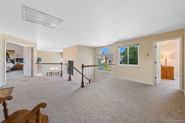 hallway featuring light carpet and a textured ceiling