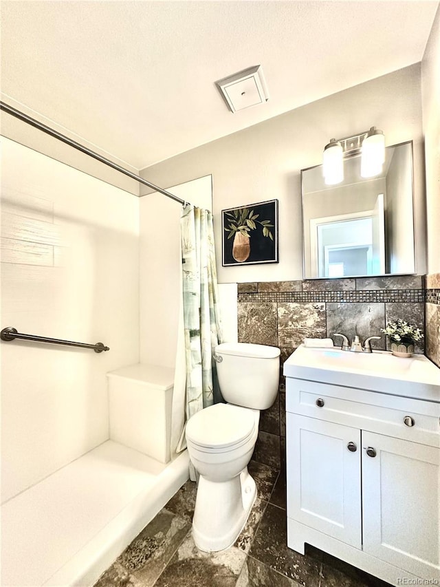 bathroom featuring vanity, toilet, walk in shower, and tile walls