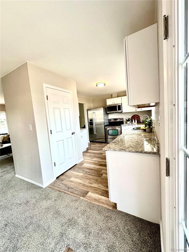 kitchen featuring white cabinets, stainless steel appliances, plenty of natural light, and light hardwood / wood-style floors