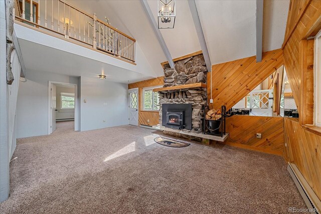 80 Castlewood Ct, Evergreen, CO 80439 - unfurnished living room featuring a baseboard radiator, a towering ceiling, wooden walls, healthy amount of natural light, and carpet flooring