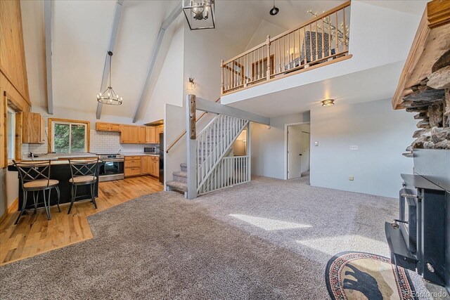 80 Castlewood Ct, Evergreen, CO 80439 - living room with high vaulted ceiling, stairway, light colored carpet, a chandelier, and light wood finished floors