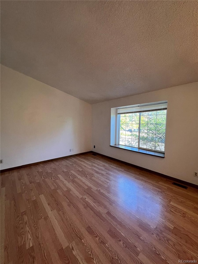 unfurnished room with a textured ceiling and hardwood / wood-style floors