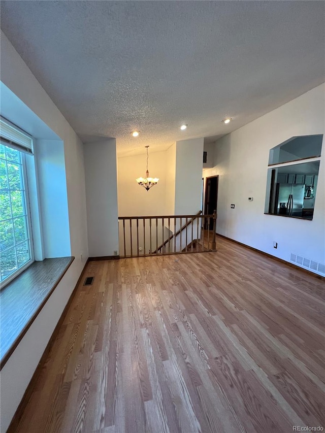 bonus room featuring wood-type flooring, a chandelier, and a textured ceiling