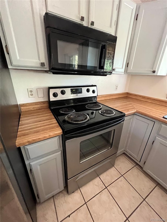 kitchen featuring stainless steel range with electric stovetop, butcher block countertops, light tile patterned floors, and gray cabinetry