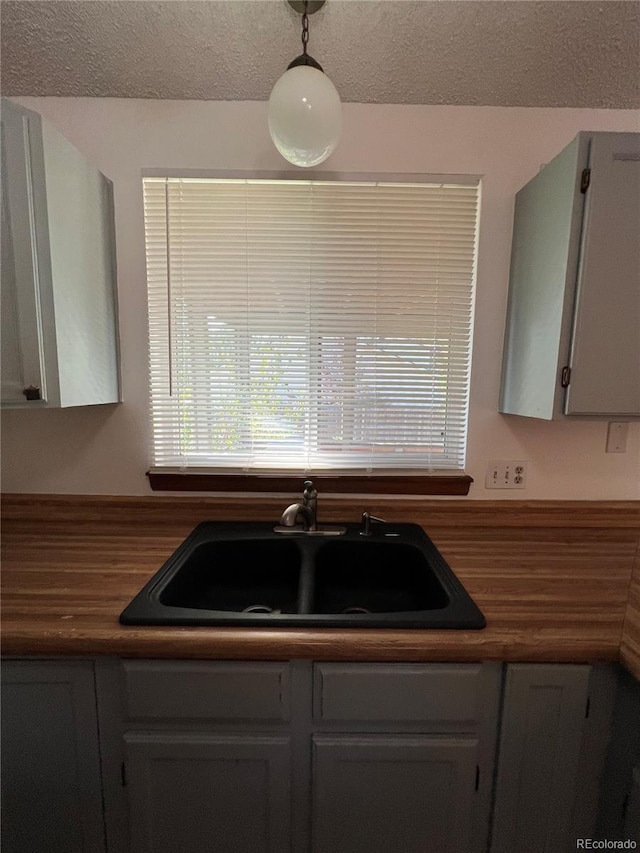 kitchen featuring butcher block counters, gray cabinets, and hanging light fixtures