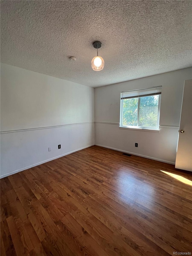 empty room featuring dark wood-type flooring and a textured ceiling