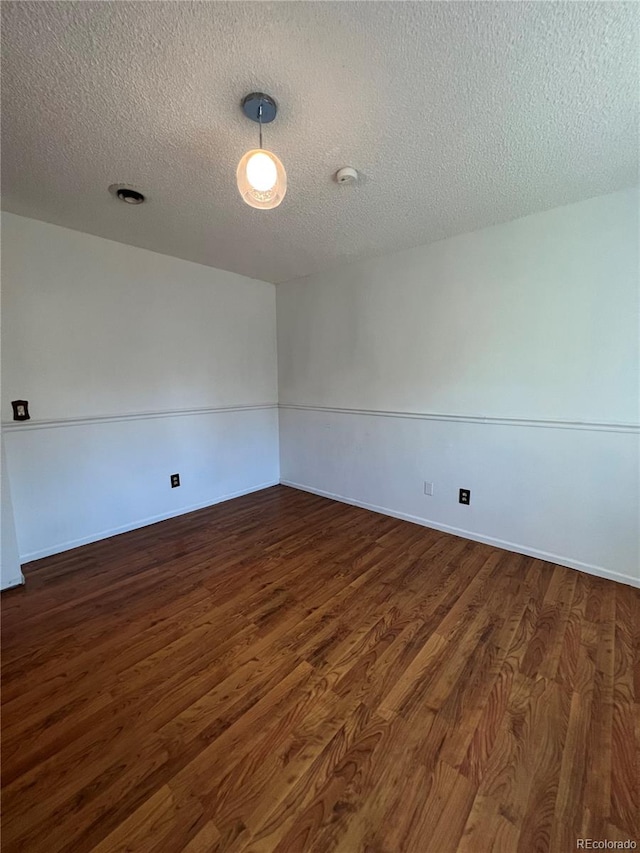 unfurnished room with dark wood-type flooring and a textured ceiling