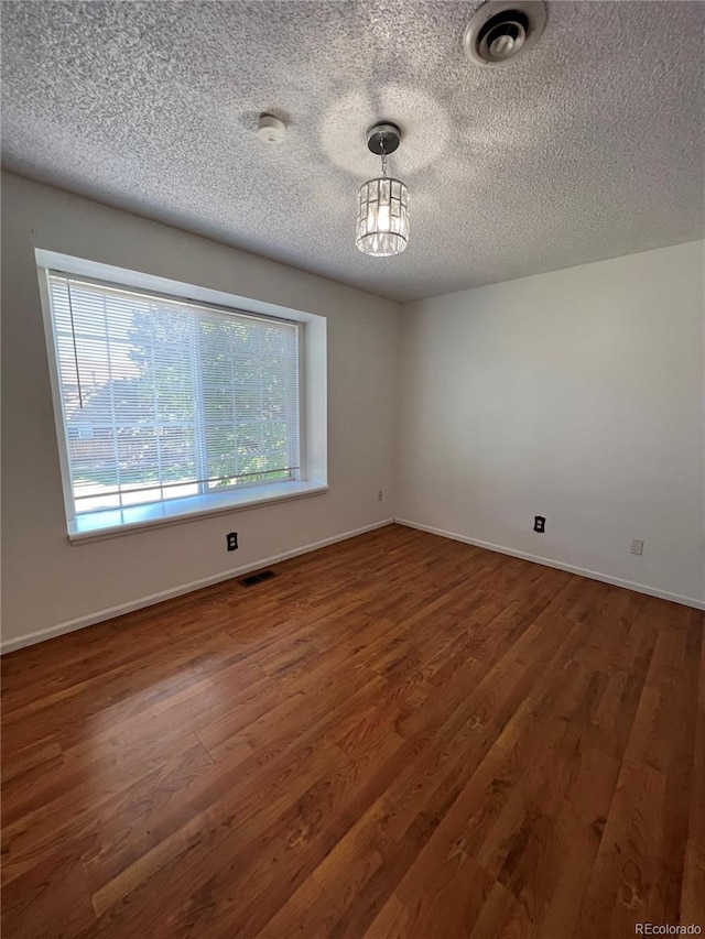 empty room with a textured ceiling and dark hardwood / wood-style floors