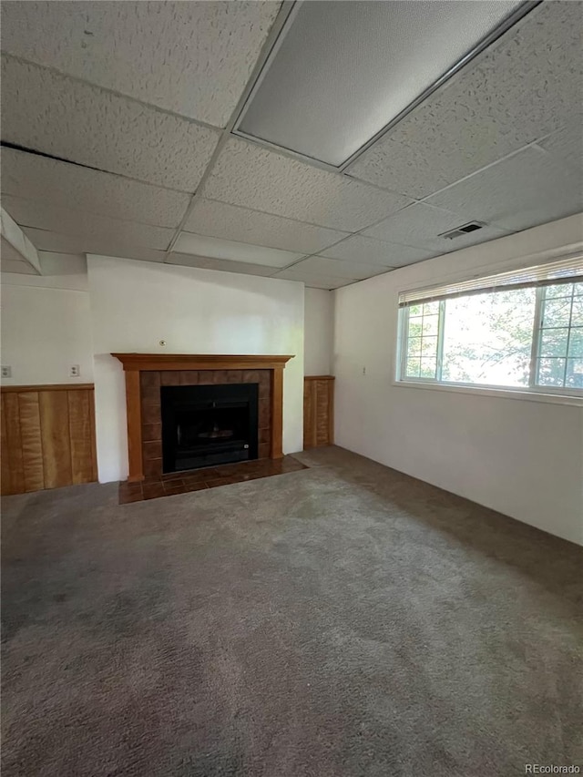 unfurnished living room with a fireplace, carpet, and a drop ceiling