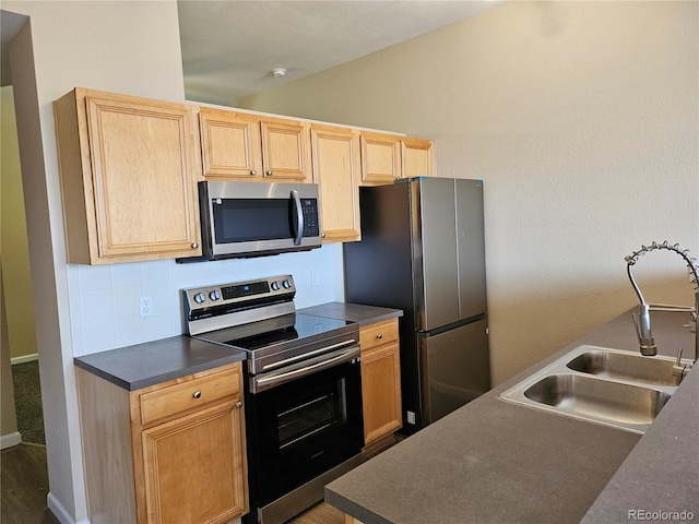 kitchen featuring sink, appliances with stainless steel finishes, backsplash, light brown cabinetry, and vaulted ceiling