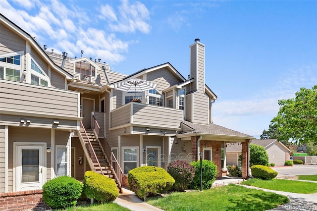 view of front of property featuring stairway, a chimney, and brick siding