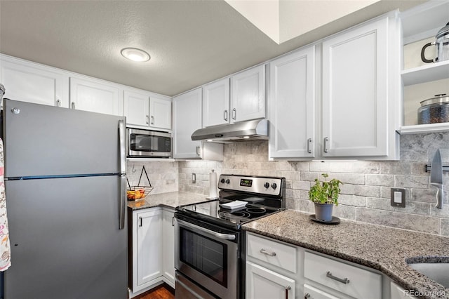 kitchen featuring appliances with stainless steel finishes, under cabinet range hood, white cabinetry, stone countertops, and tasteful backsplash