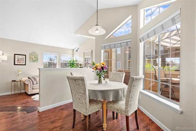 dining space featuring high vaulted ceiling, wood finished floors, and baseboards