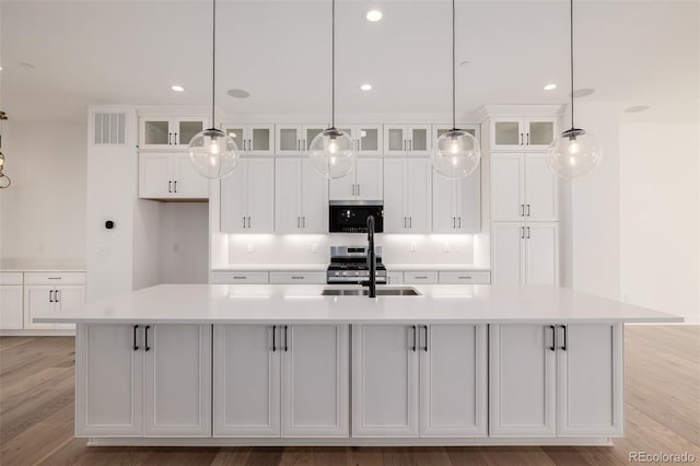 kitchen with light wood-type flooring, visible vents, white cabinets, gas range, and a spacious island