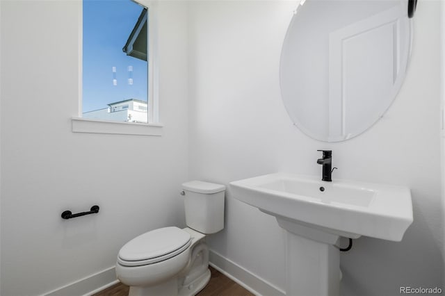 bathroom with toilet, wood finished floors, and baseboards