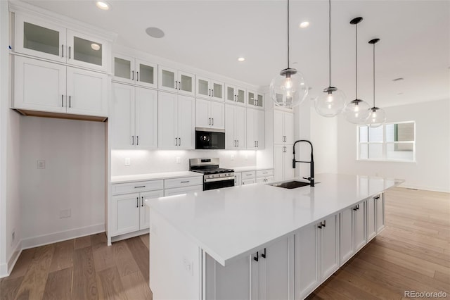 kitchen with light wood finished floors, white cabinetry, a sink, and appliances with stainless steel finishes