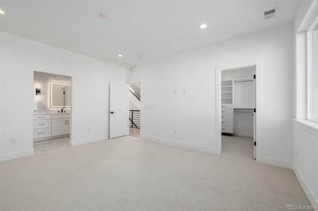 unfurnished bedroom with visible vents, recessed lighting, a walk in closet, and light carpet