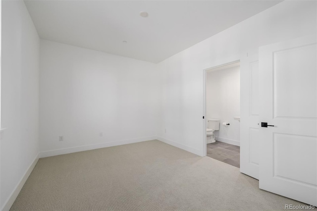 spare room featuring light carpet and baseboards