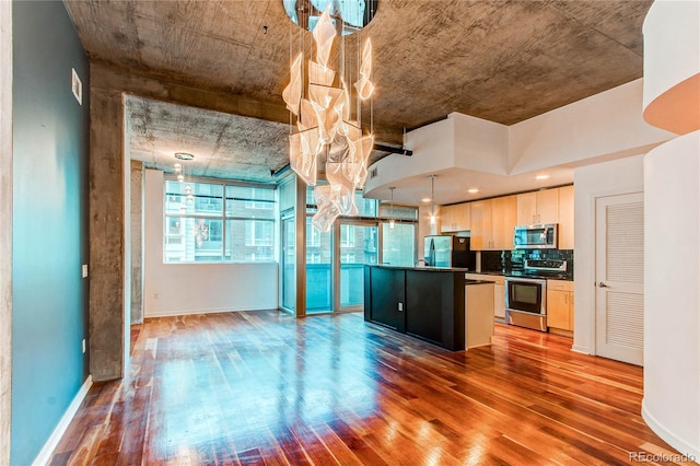 kitchen with hanging light fixtures, an island with sink, hardwood / wood-style flooring, and stainless steel appliances