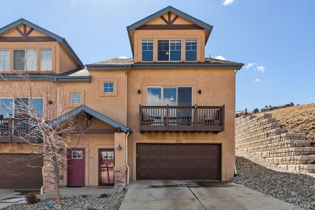 view of front of home featuring driveway, a balcony, an attached garage, and stucco siding