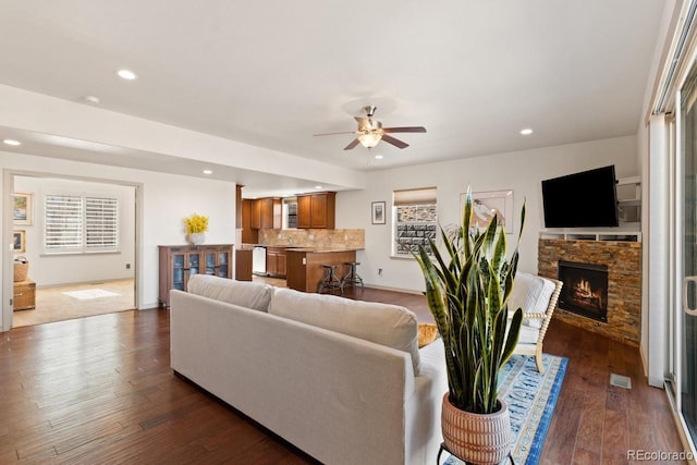 living room with recessed lighting, a ceiling fan, dark wood-type flooring, and a stone fireplace