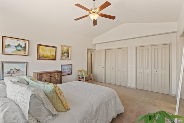 bedroom featuring a ceiling fan, light carpet, vaulted ceiling, and two closets