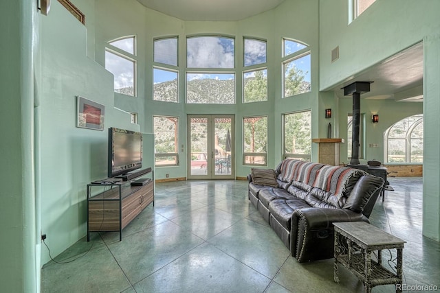 living room featuring a towering ceiling, french doors, and a wood stove